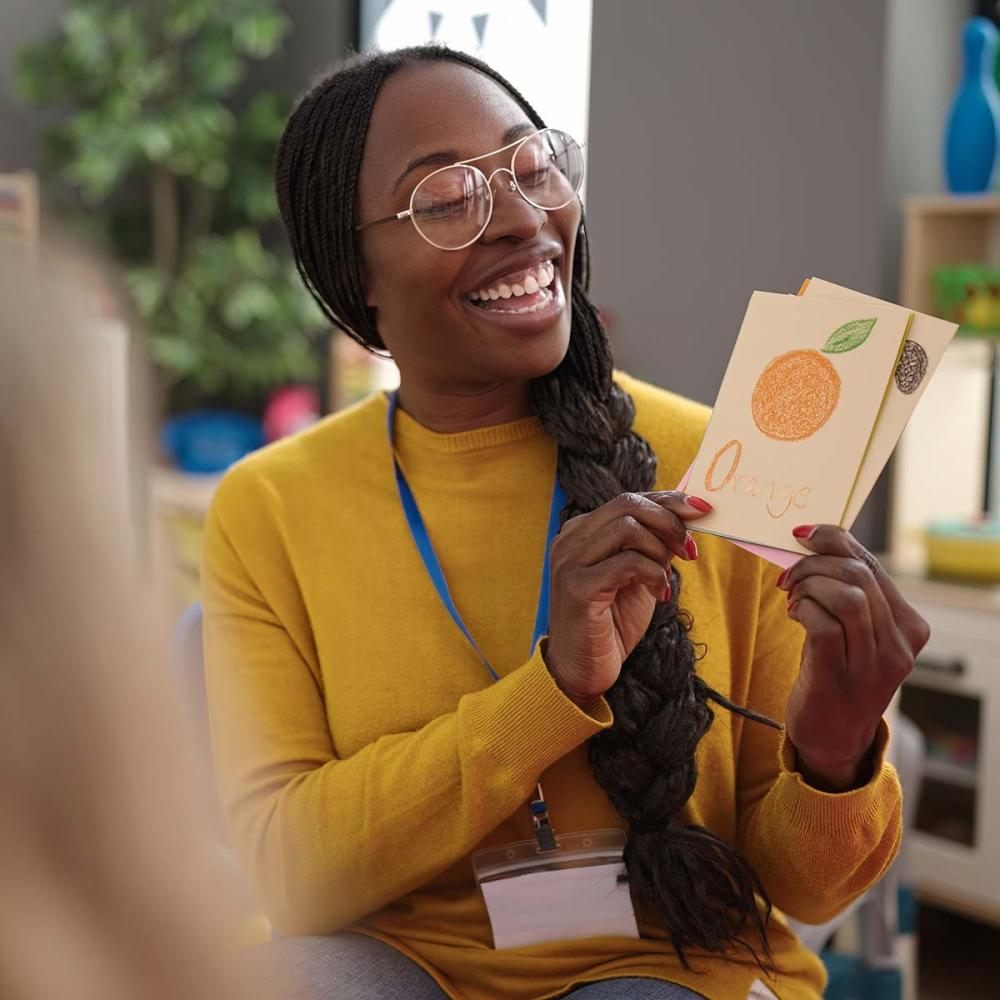Childcare educator holding flash cards and smiling